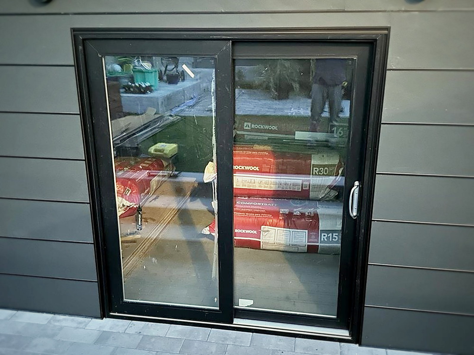 Sliding glass door installed in the soundproof studio shed with Rockwool insulation batts stacked inside