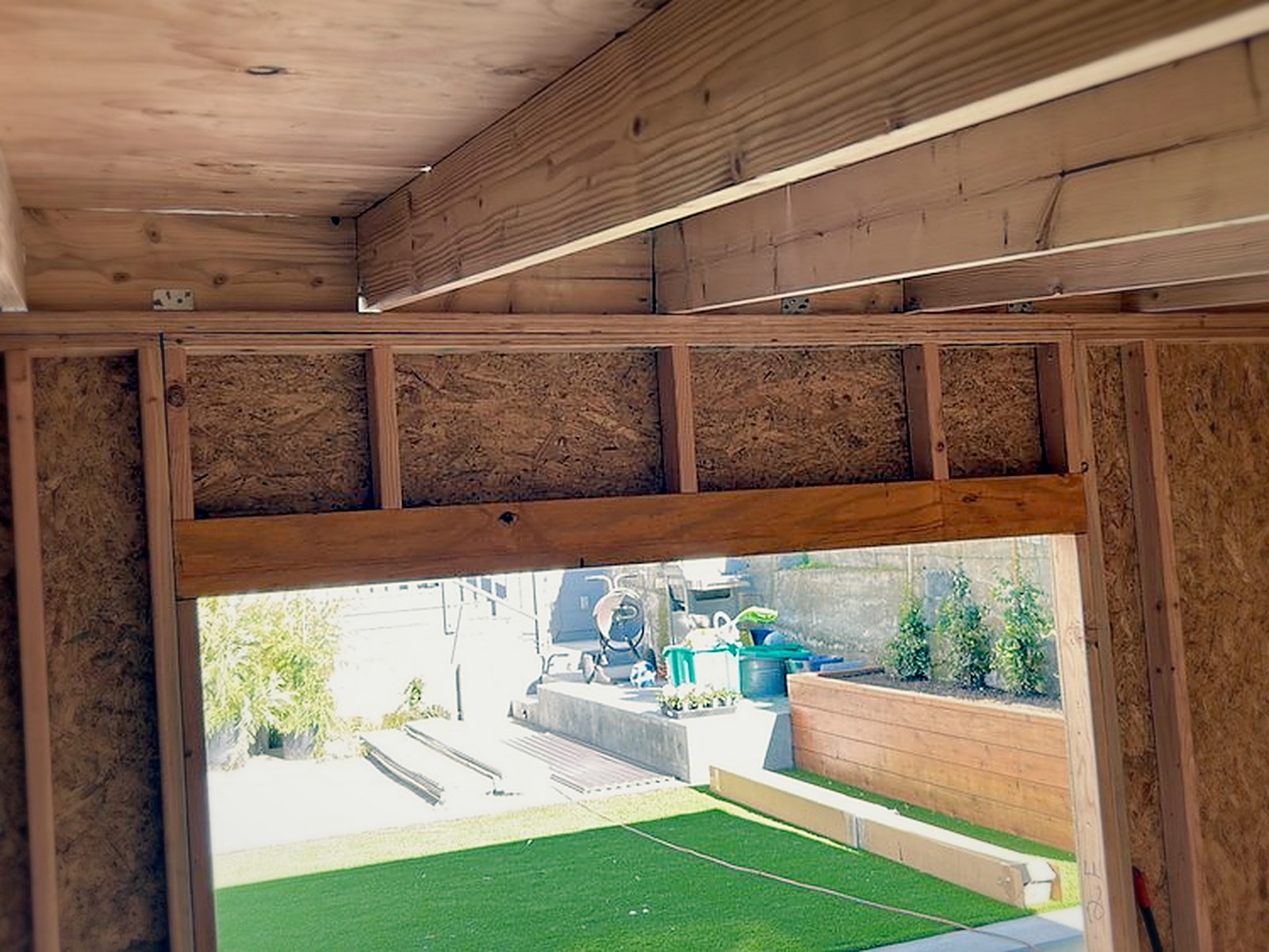 Framed door opening inside the soundproof studio shed looking out to the backyard lawn before insulation