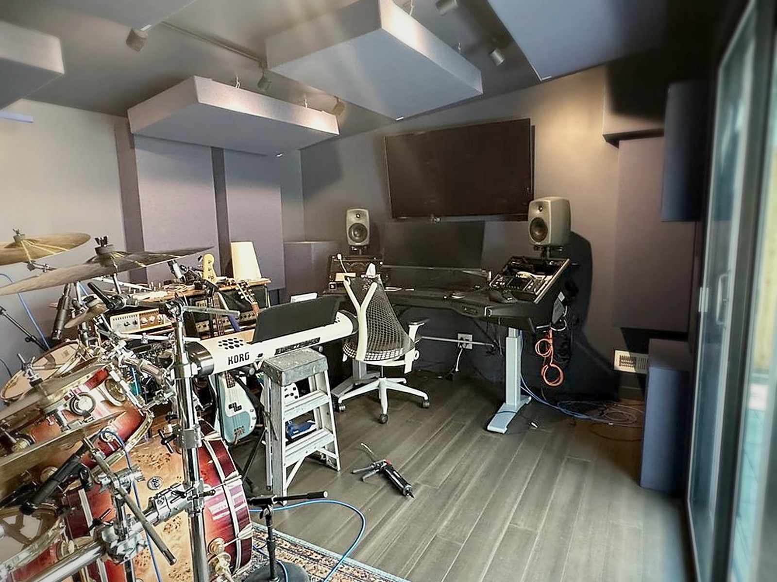 Finished backyard music studio shed interior with acoustic ceiling clouds, wall panels, mixing desk and drum kit