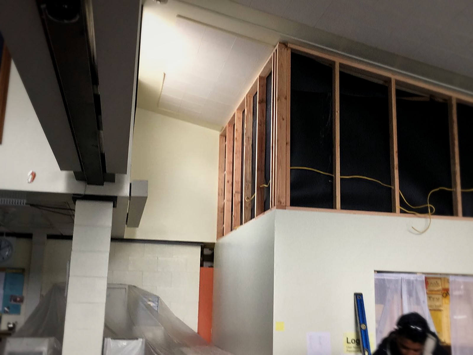 New stud framing and membrane filling the transom opening above a Melrose classroom wall