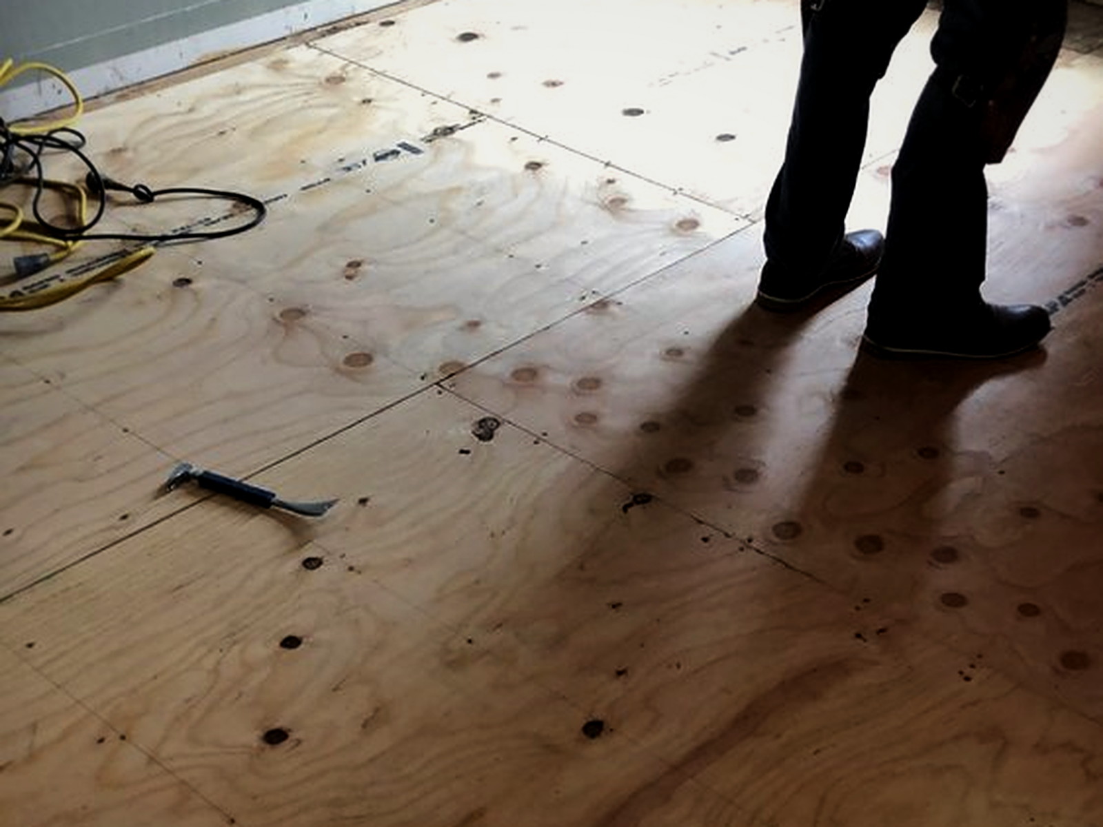 New plywood subfloor layer screwed down over insulated floor joists in a residential soundproofing project