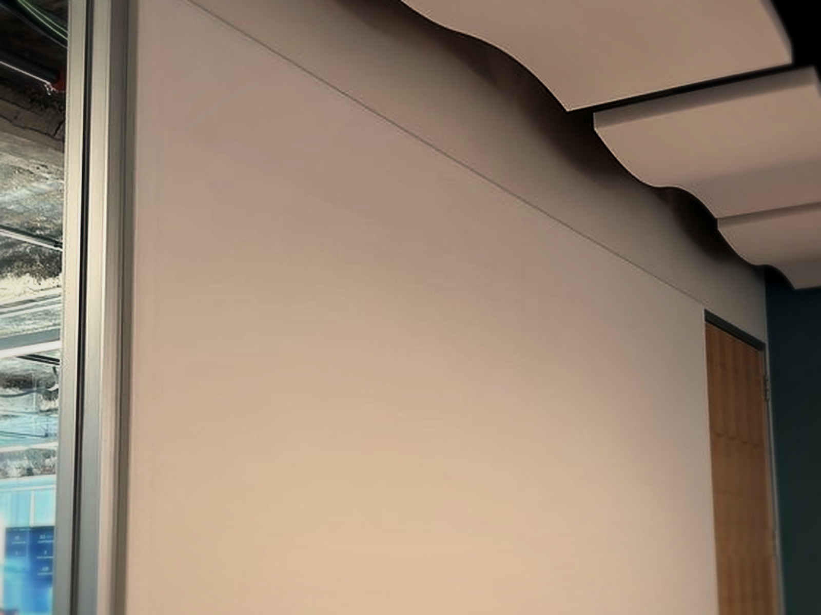 White fabric track acoustic wall panel next to suspended wave ceiling clouds in a San Francisco office conference room