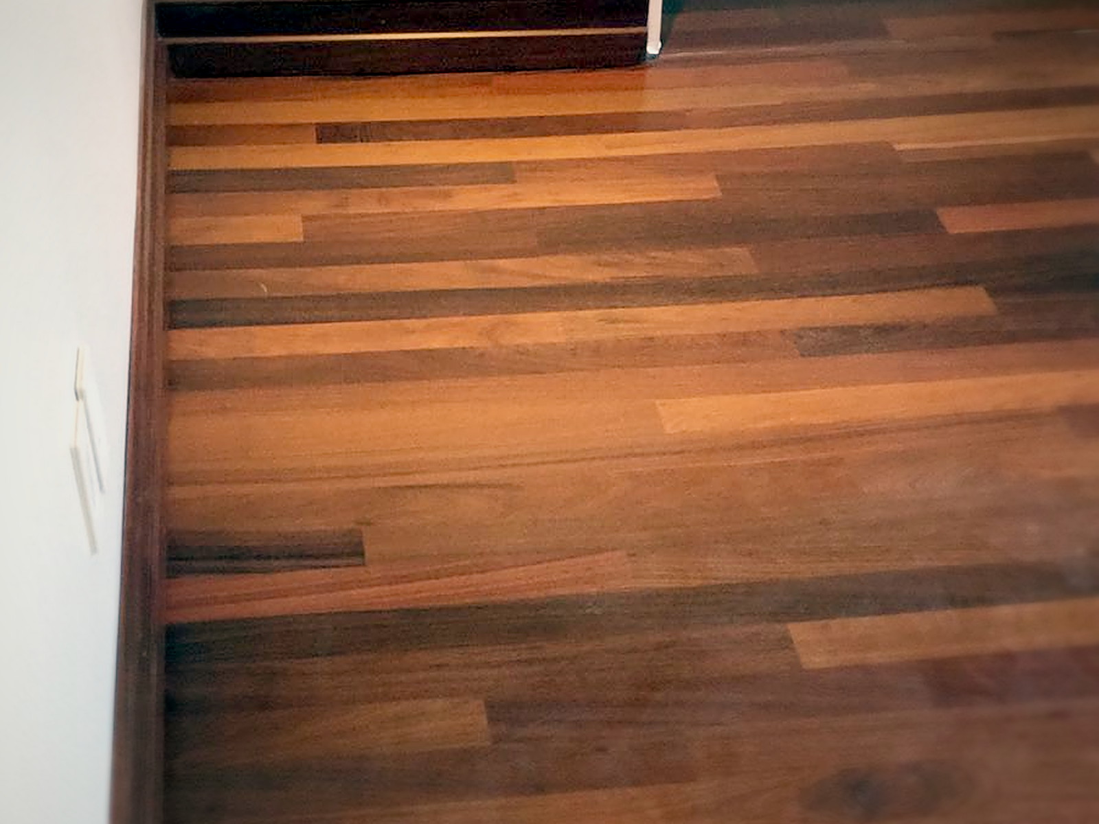 New hardwood floor and baseboard meeting a finished soundproofed wall in a Melrose residence