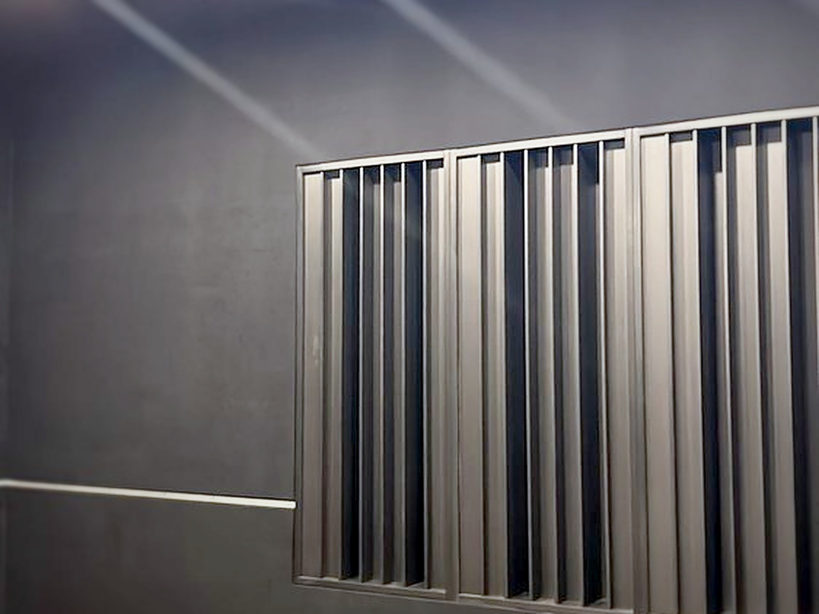 Finished San Francisco recording studio wall with charcoal fabric track panels and a black slat diffuser under warm lighting