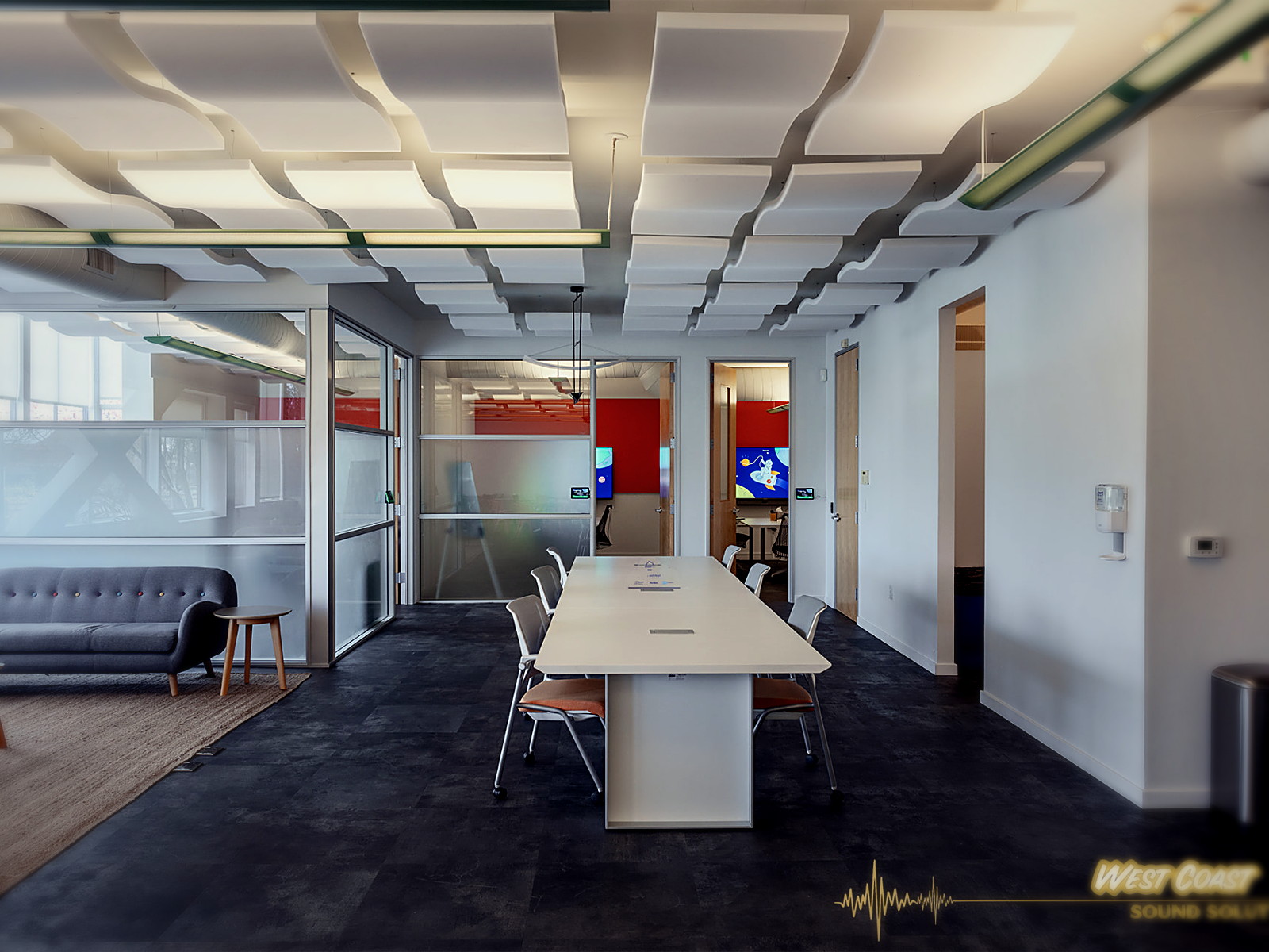 Berkeley office boardroom table under a dense grid of wave-form acoustic ceiling clouds beside a glass-walled lounge