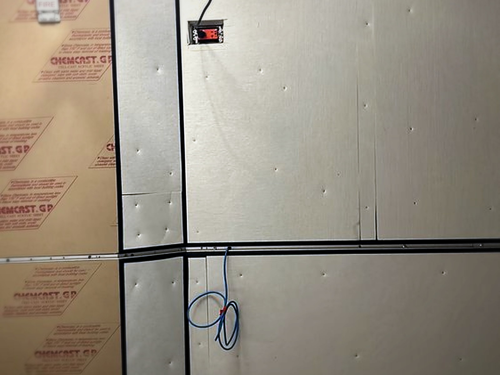 Studio wall panels being fitted with taped seams and temporary wiring during the acoustic rebuild