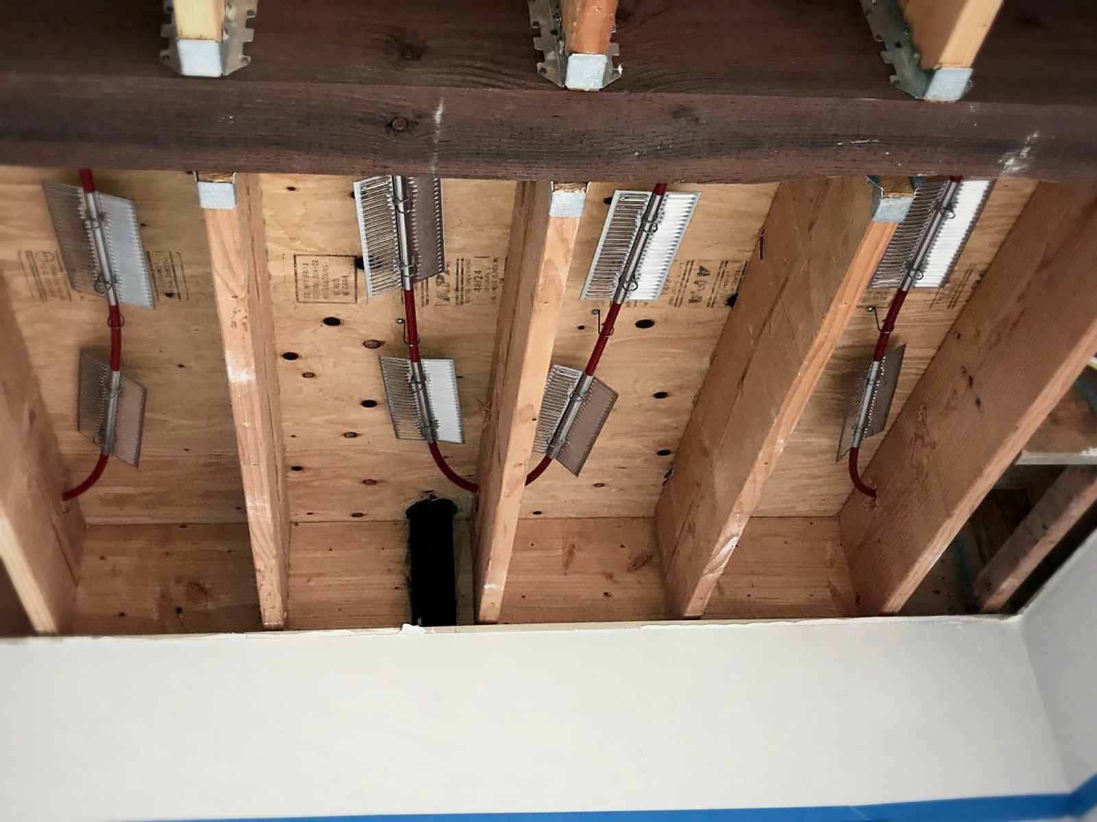Open residential ceiling in San Francisco with exposed floor joists and plywood subfloor above before soundproofing