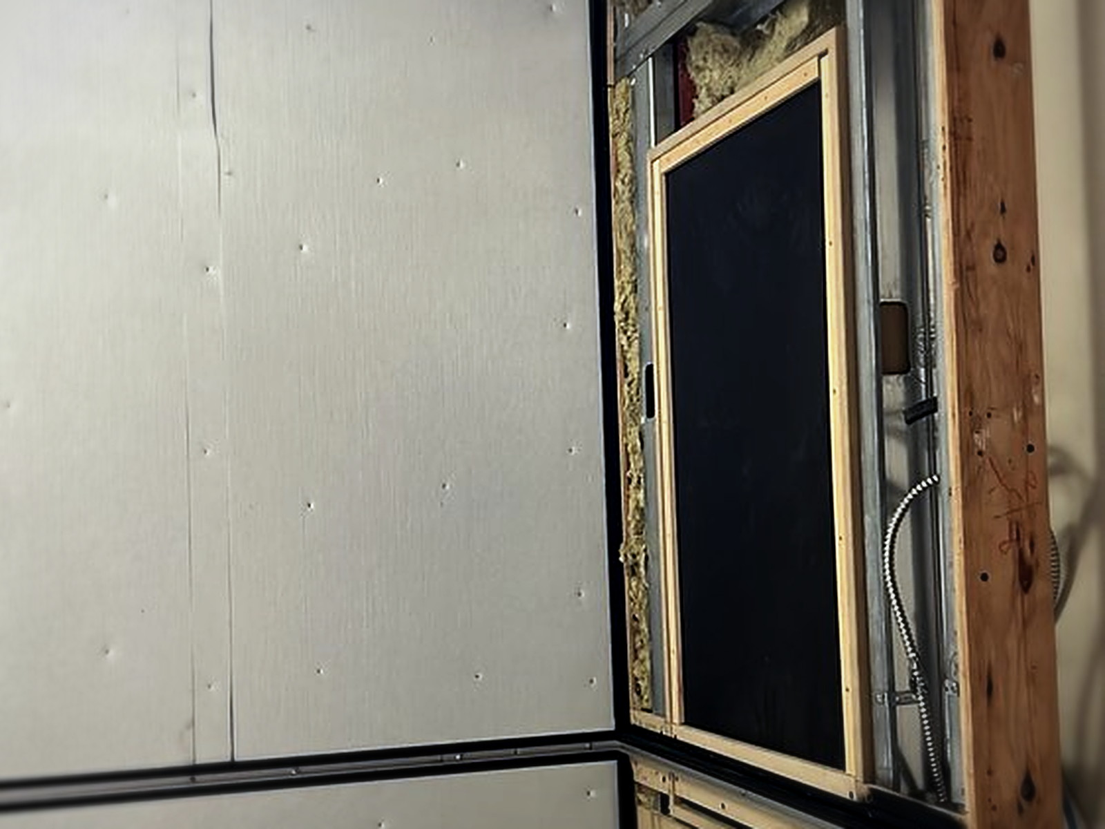 Acoustic wall buildup in progress with mineral wool insulation between metal studs and gypsum panels going up
