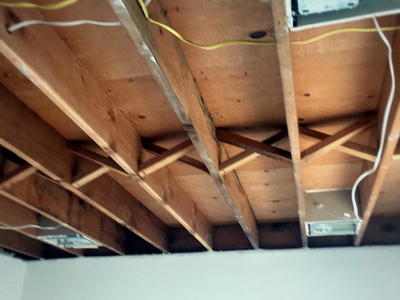 Classroom ceiling opened to bare wood joists and cross bracing before insulation at Bridges Academy