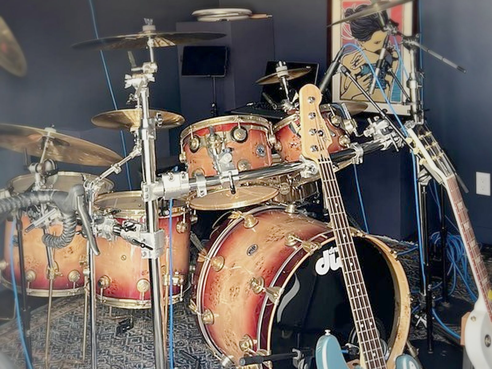 Drum kit under gray acoustic ceiling clouds in the completed soundproof backyard studio shed with mic stands and guitars