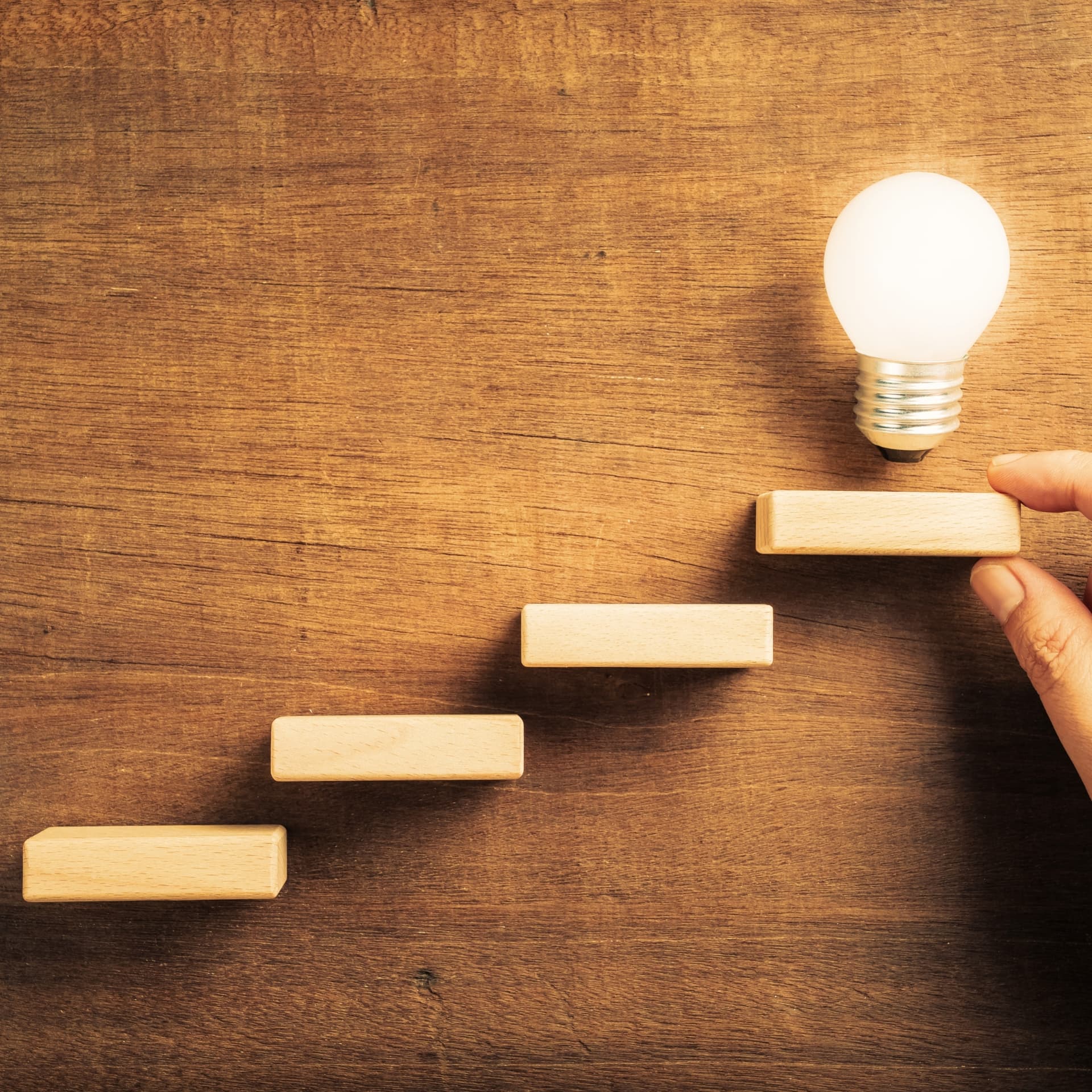 Wooden blocks arranged as ascending stairs with a lit bulb — step-by-step soundproofing build guides.