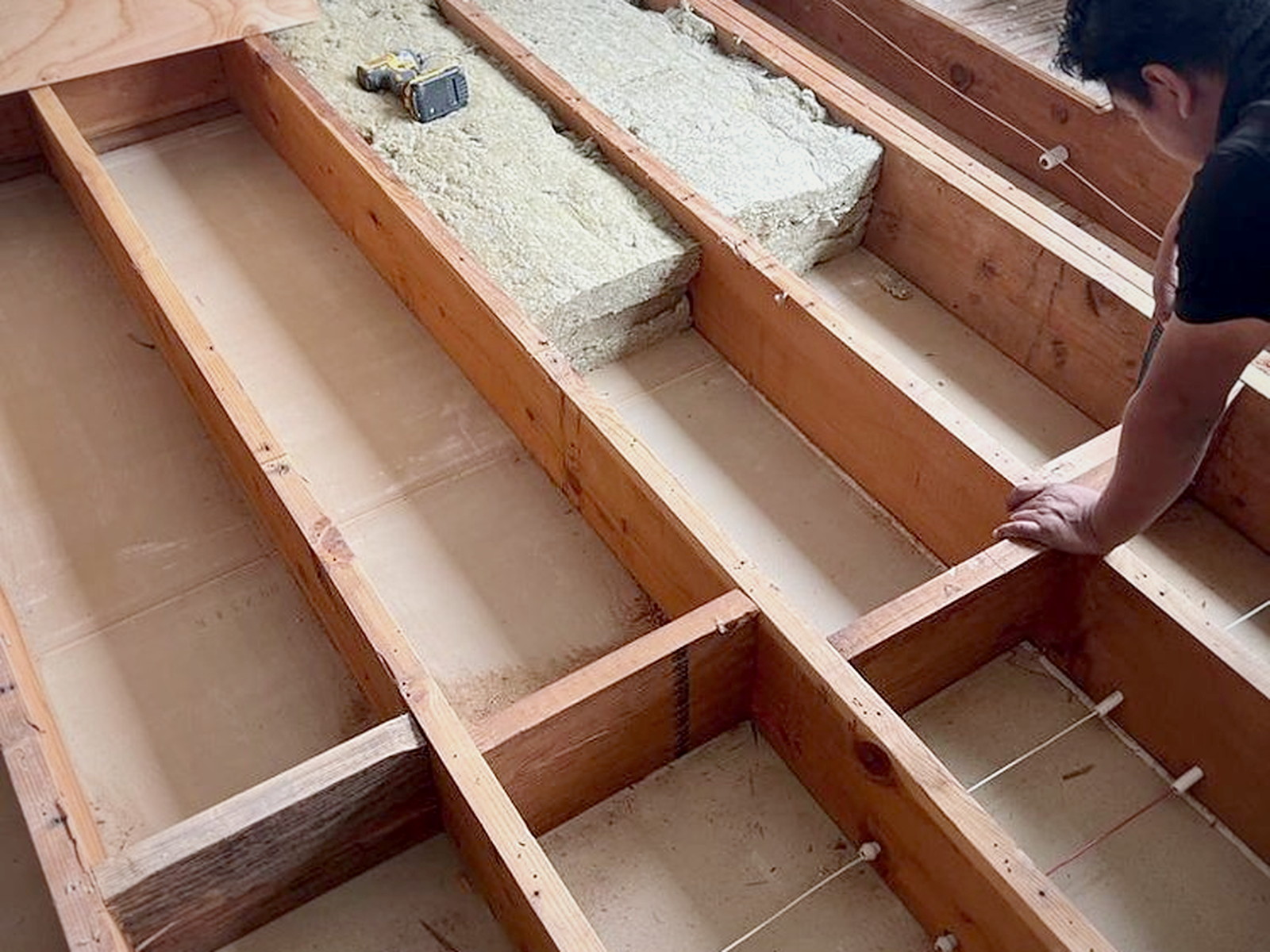 Rockwool Safe'n'Sound mineral wool batts being fitted between open floor joists before the new subfloor goes down