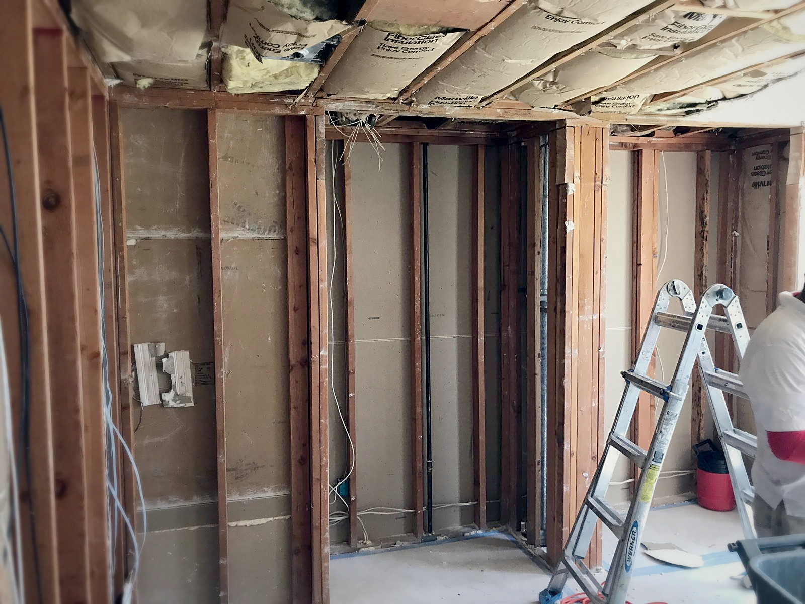 Melrose residential room stripped to bare studs and joists with old fiberglass insulation before soundproofing