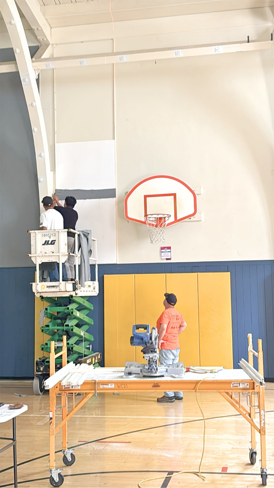 West Coast Sound Solutions crew installing custom fabric track acoustic panels from a scissor lift in the YMCA gym
