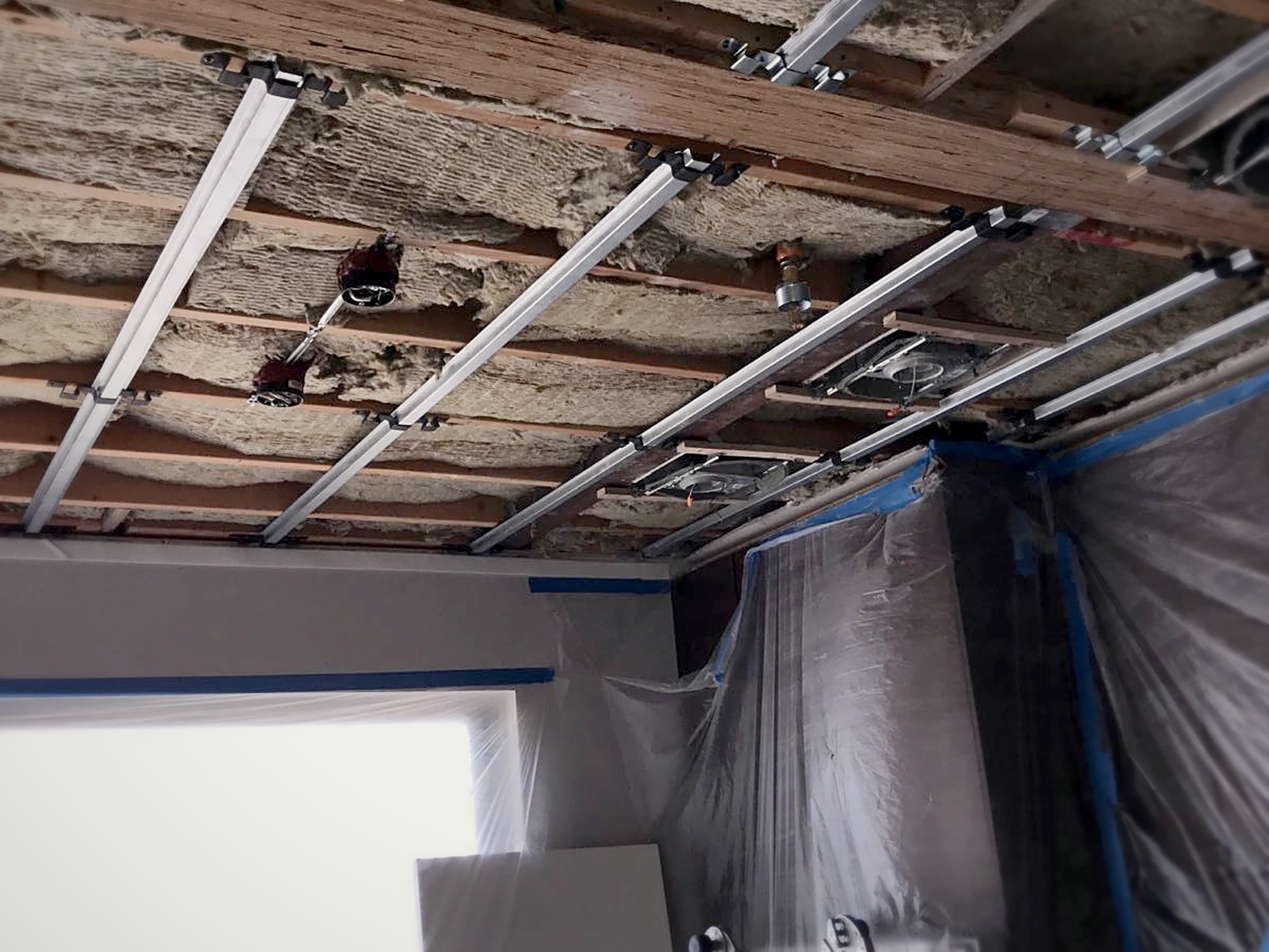 Sound isolation clips and hat channel installed across an insulated San Francisco residential ceiling before drywall
