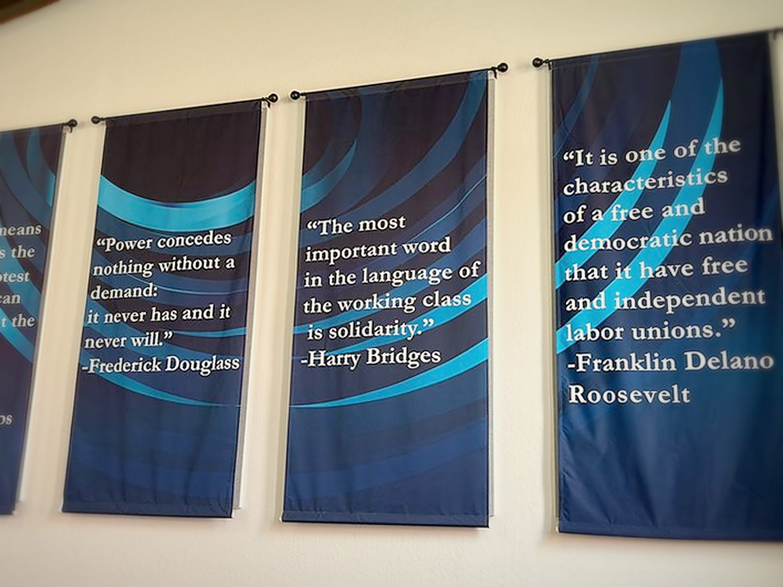 Wall banners rehung over completed custom fabric track acoustic panels in an Oakland institutional meeting room