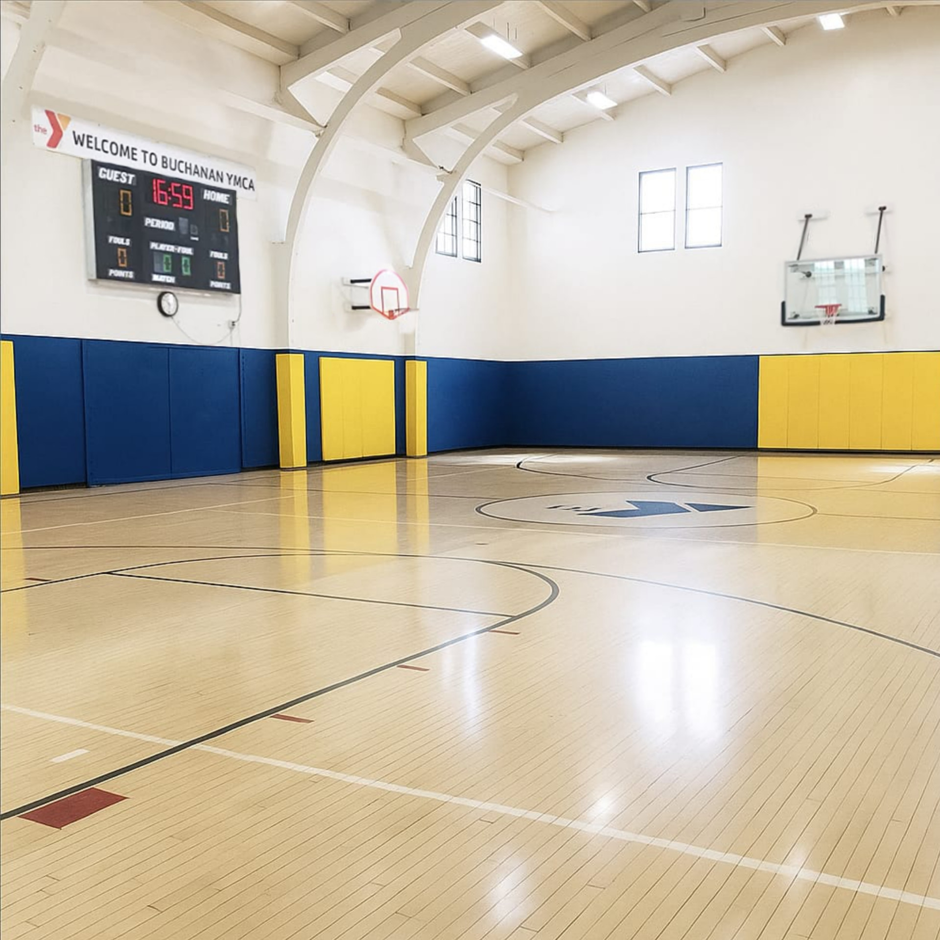 Buchanan YMCA gymnasium before acoustic treatment with bare reflective white walls and wood floor
