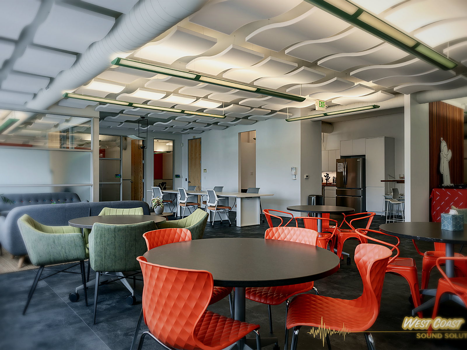 Berkeley office cafe with orange and green seating under a wide field of wave acoustic ceiling clouds and linear pendants