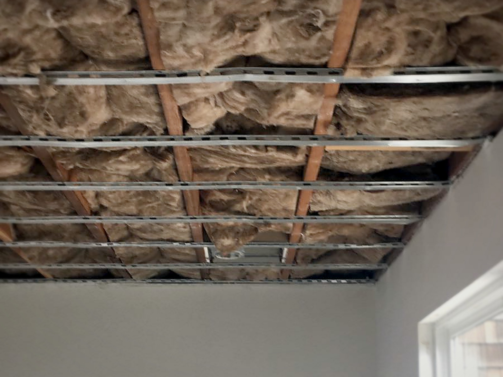 Classroom ceiling at Bridges Academy packed with mineral wool insulation and fitted with hat channel before drywall
