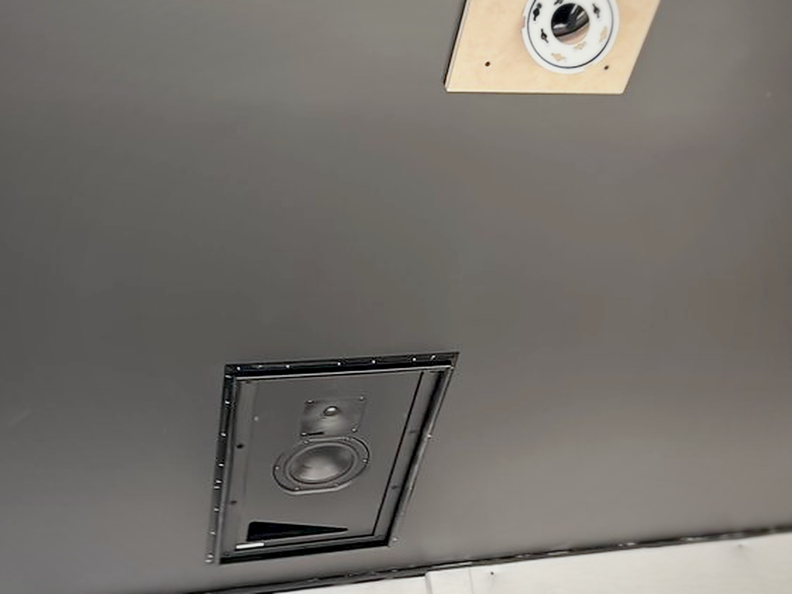 Flush-mount studio monitor being installed into a pre-cut opening in the acoustic ceiling of the recording studio