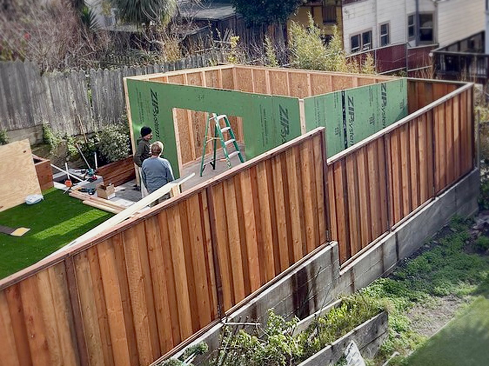 Crew framing the backyard soundproof studio shed walls with ZIP System sheathing on a new concrete pad in San Francisco