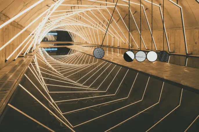 Light-lined tunnel with acoustic sample discs suspended along the wall — acoustic design and treatment
