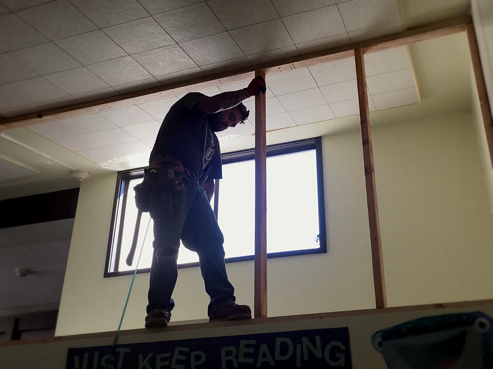 Installer standing on a classroom partition framing the transom opening closed at Bridges Academy
