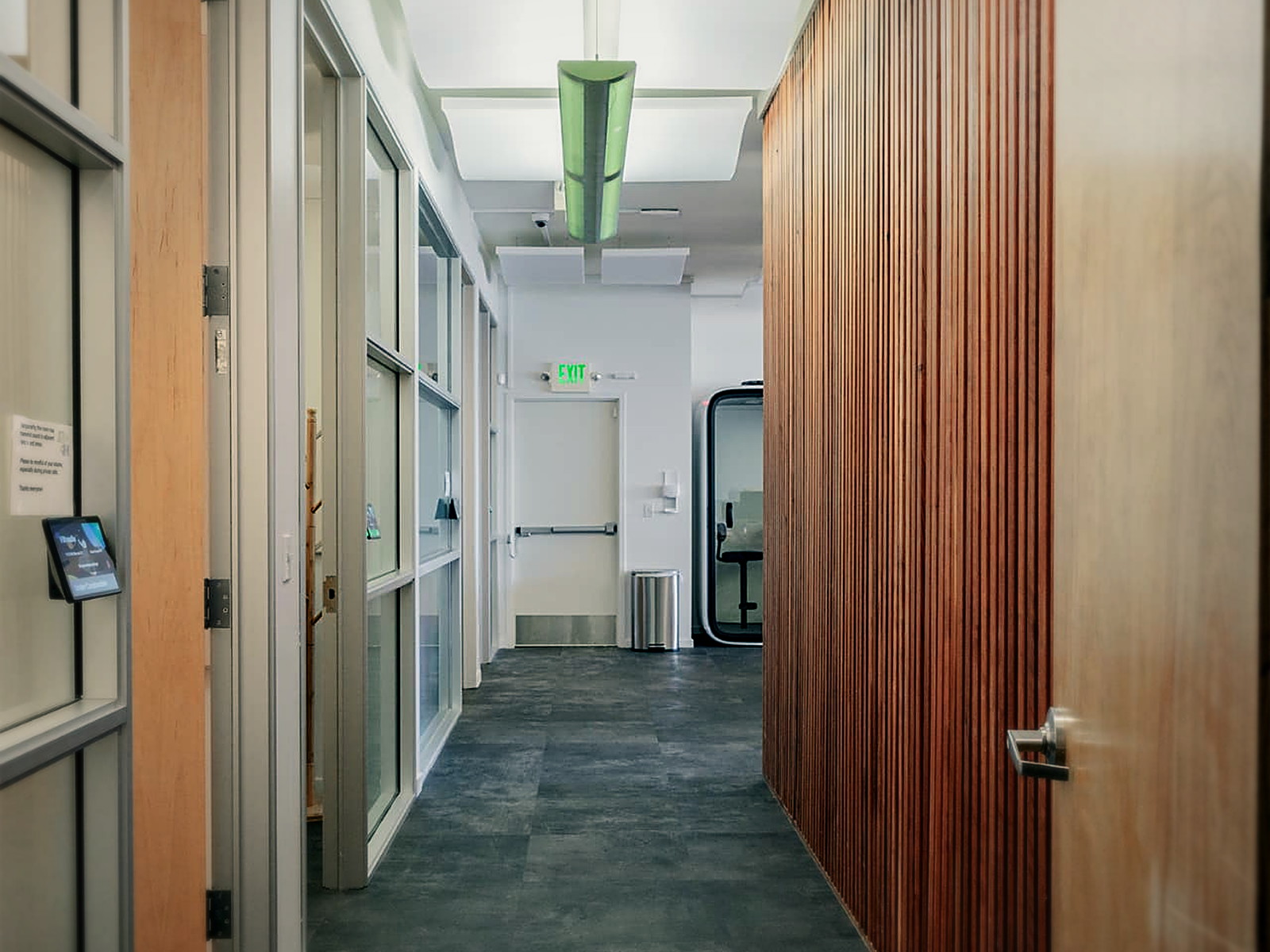 Office corridor in a Berkeley commercial floor with hard tile flooring, glass partitions and ceiling acoustic clouds overhead