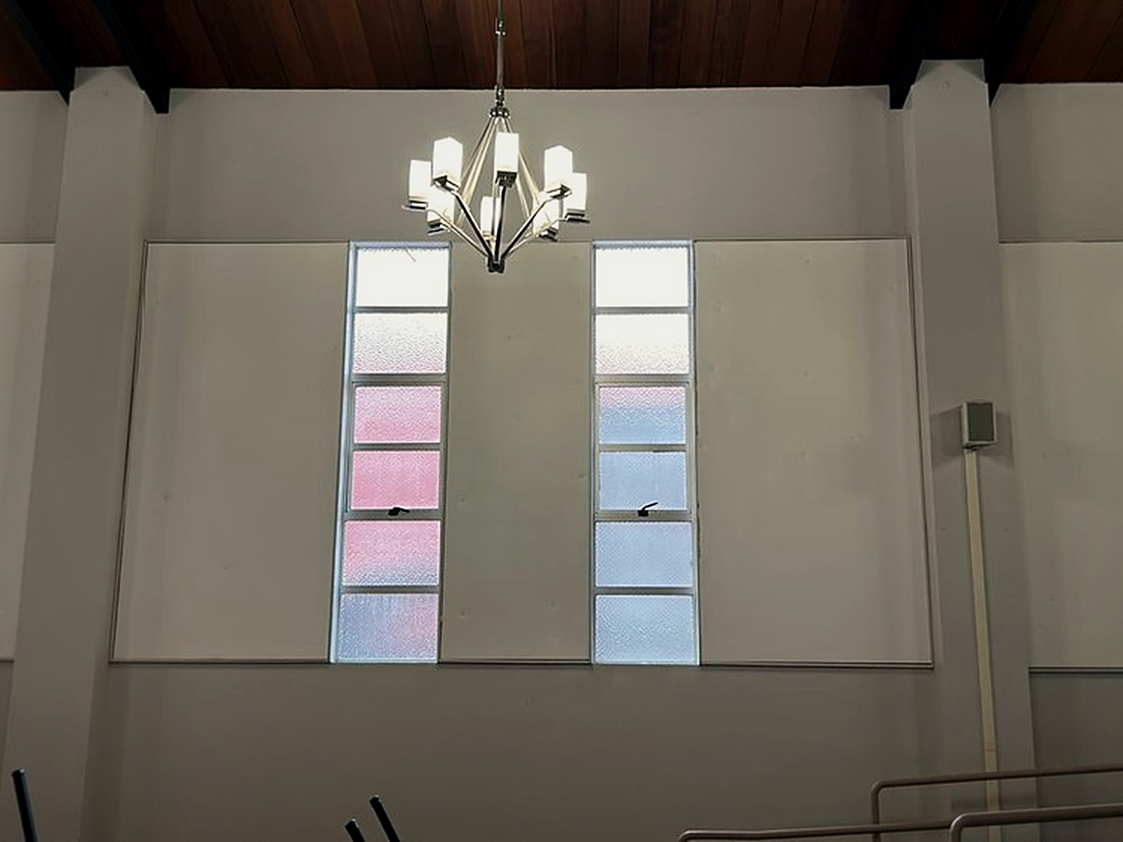 Fabric track acoustic panels installed in the wall bays between tall institutional windows